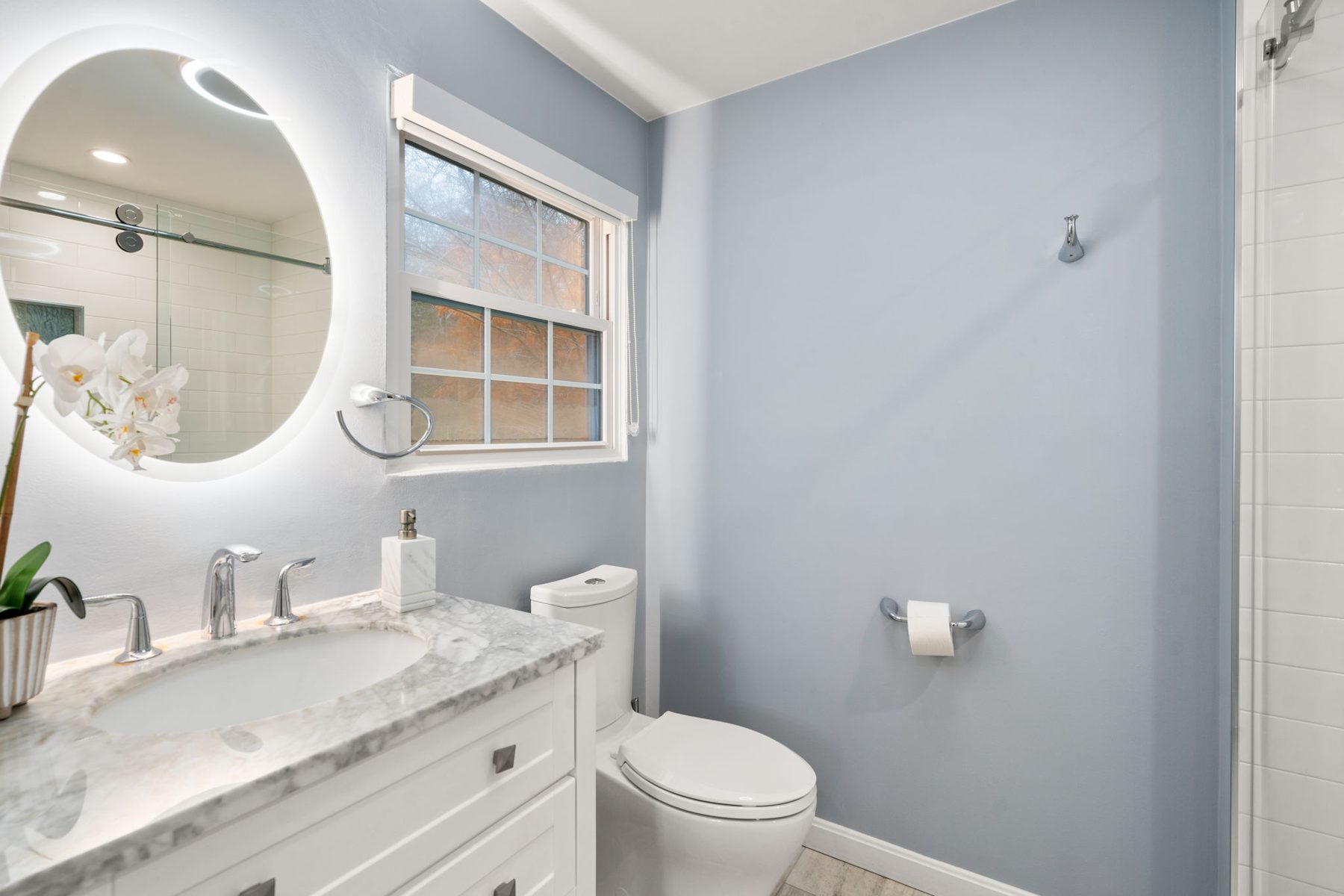 Condor guest bath — marble vanity, lit round mirror — after
