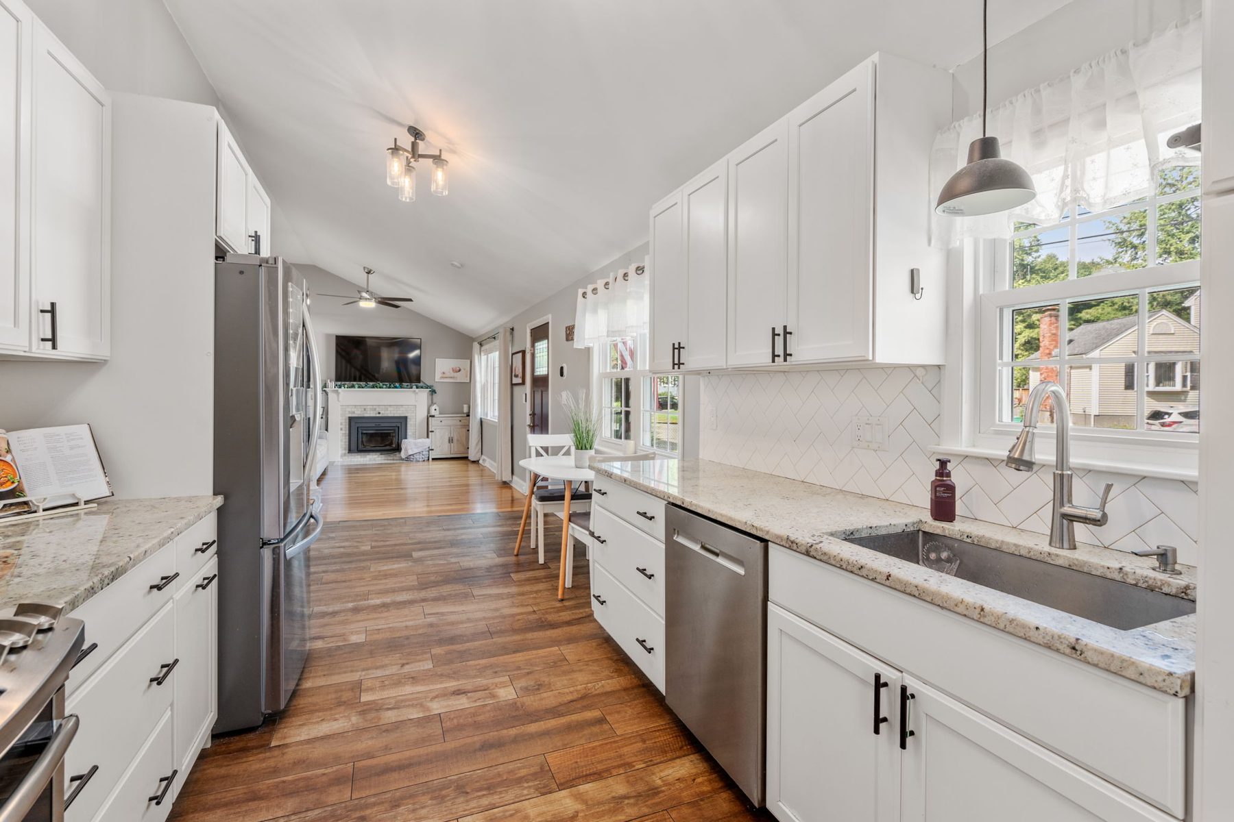 Skelton kitchen — white shaker, granite, herringbone tile, a cookbook open on purpose — after